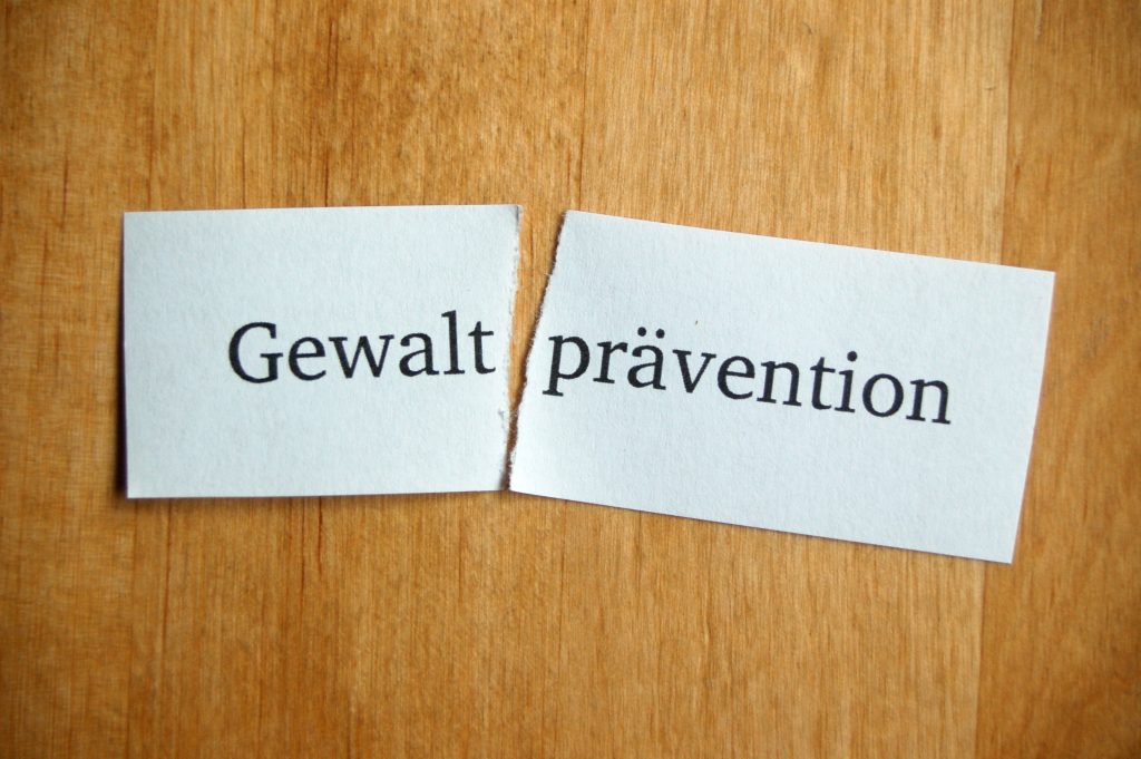 Ein Stück Papier mit dem Aufdruck Gewaltprävention Das Papier ist zwischen Gewalt und prävention zerrissen.