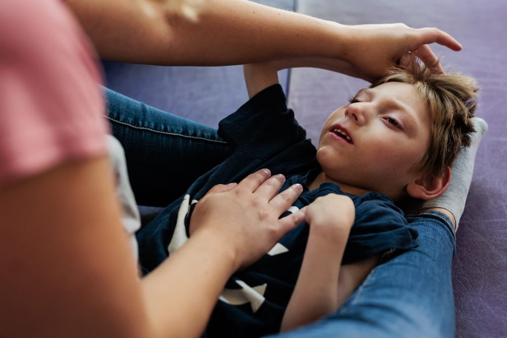 Ein kleiner Junge liegt bei der Physiotherapie auf einer Matte. 